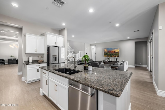 kitchen with visible vents, a sink, light wood-style floors, stainless steel dishwasher, and refrigerator with ice dispenser