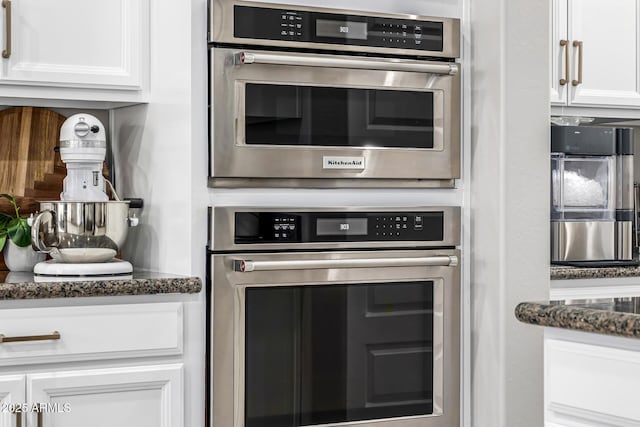 kitchen with dark stone countertops, white cabinetry, and oven