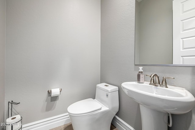 bathroom with a sink, baseboards, and toilet