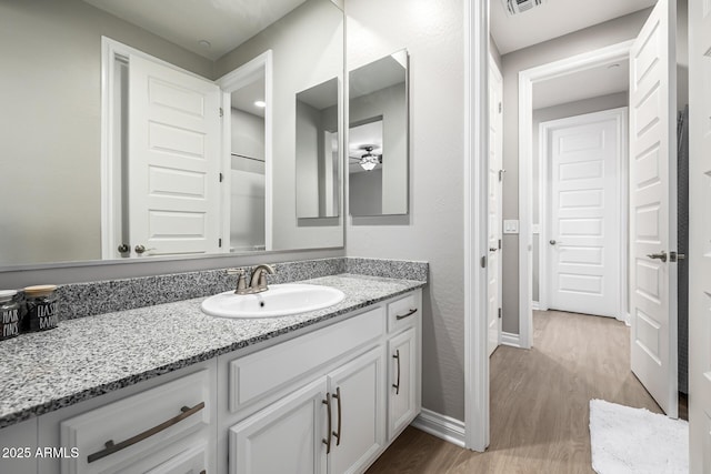 bathroom featuring baseboards, vanity, a ceiling fan, and wood finished floors