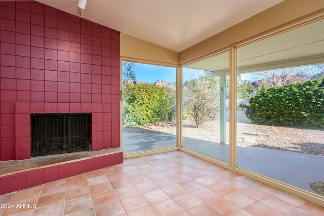 unfurnished sunroom with lofted ceiling, a fireplace, and a healthy amount of sunlight