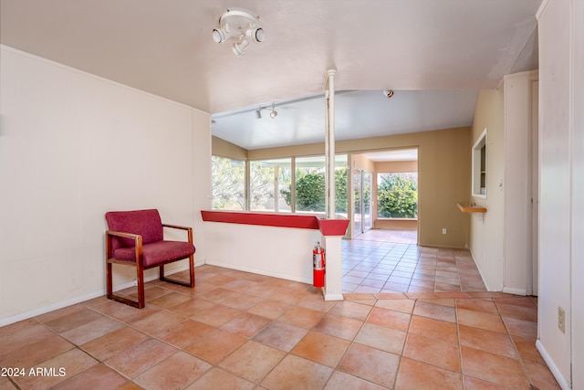 living area featuring track lighting, lofted ceiling, and light tile patterned flooring