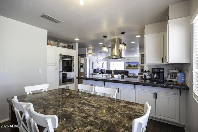14484 W Jimmie Kerr Blvd, Casa Grande, AZ 85122 - kitchen with stainless steel double oven, a peninsula, island exhaust hood, white cabinets, and recessed lighting
