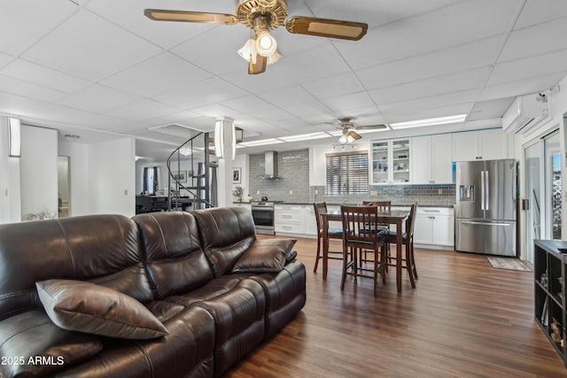 living room with hardwood / wood-style flooring, a paneled ceiling, and ceiling fan