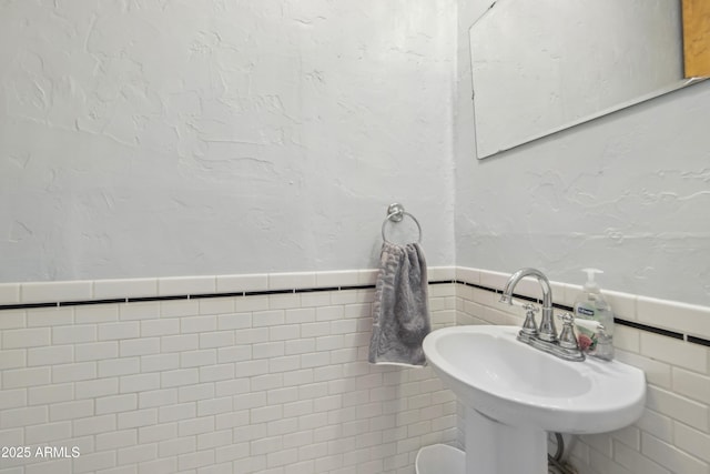 bathroom featuring sink and tile walls