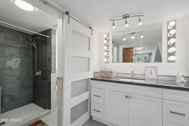 bathroom featuring tiled shower and vanity