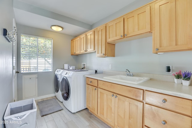 laundry room featuring sink, cabinets, light hardwood / wood-style flooring, and washing machine and dryer