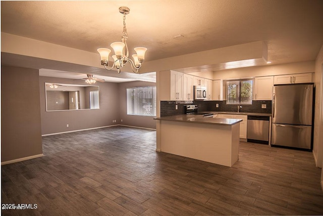 kitchen featuring tasteful backsplash, dark hardwood / wood-style floors, pendant lighting, stainless steel appliances, and white cabinets