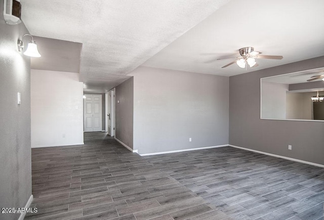 spare room with ceiling fan with notable chandelier and dark hardwood / wood-style floors