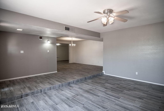 empty room with ceiling fan with notable chandelier and dark hardwood / wood-style flooring