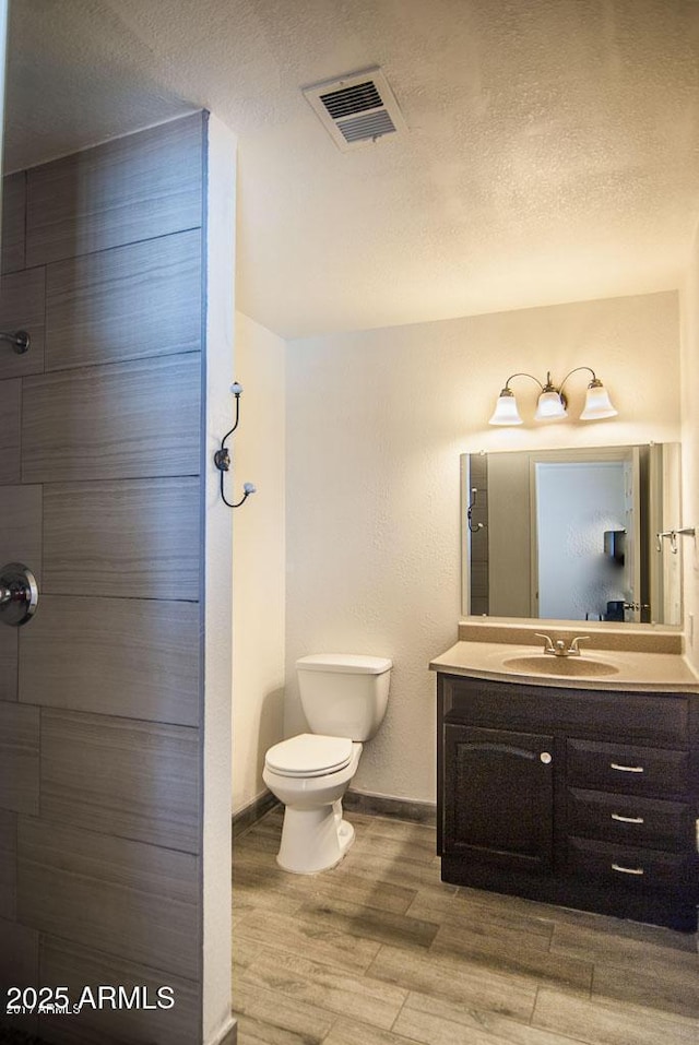 bathroom featuring vanity, toilet, hardwood / wood-style floors, and a textured ceiling