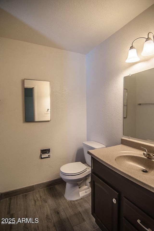 bathroom featuring vanity, hardwood / wood-style floors, a textured ceiling, and toilet