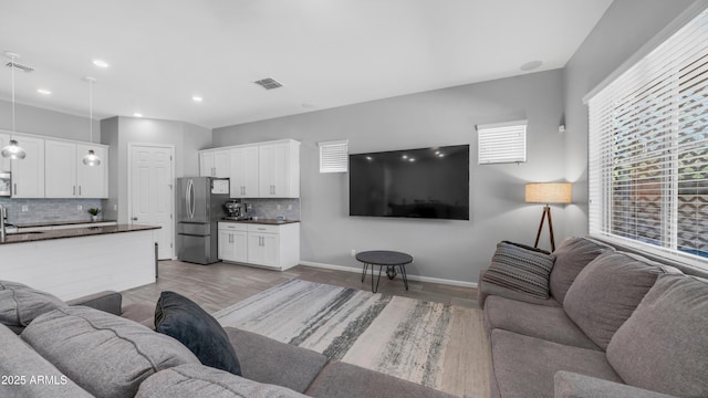 living area with baseboards, visible vents, light wood-style floors, and recessed lighting