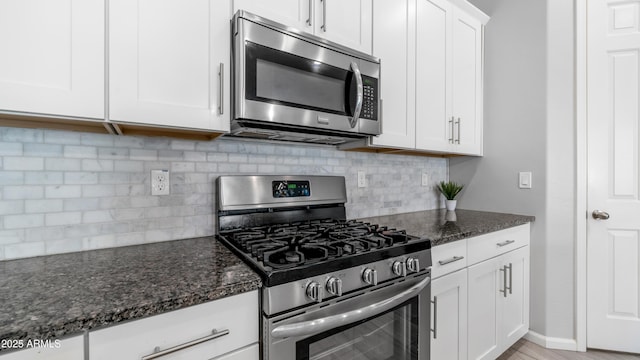 kitchen with white cabinets, stainless steel appliances, backsplash, and dark stone counters
