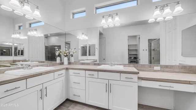 full bathroom featuring a stall shower, double vanity, a sink, and a towering ceiling