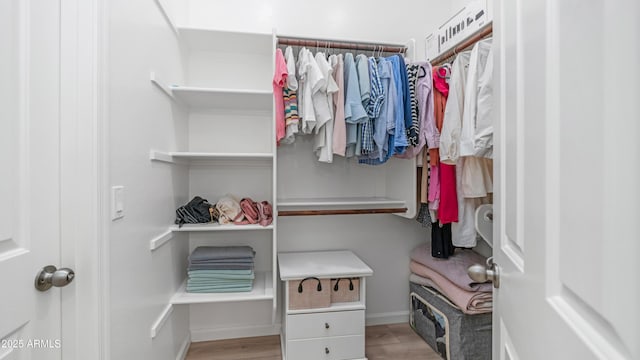 walk in closet with wood finished floors