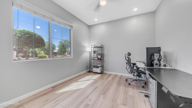 home office featuring a healthy amount of sunlight, ceiling fan, light wood finished floors, and baseboards
