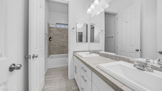 bathroom featuring toilet, shower / bathtub combination, double vanity, and a sink