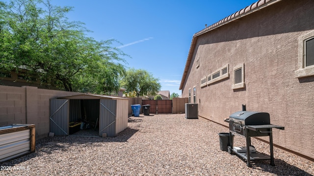 view of home's exterior with a storage unit, an outbuilding, stucco siding, central AC, and a fenced backyard