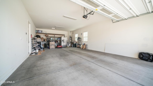 garage with a garage door opener and stainless steel fridge with ice dispenser