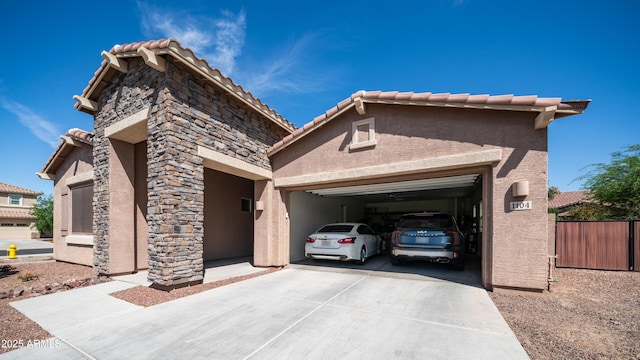 view of front of home featuring fence, concrete driveway, a tile roof, an attached garage, and stucco siding