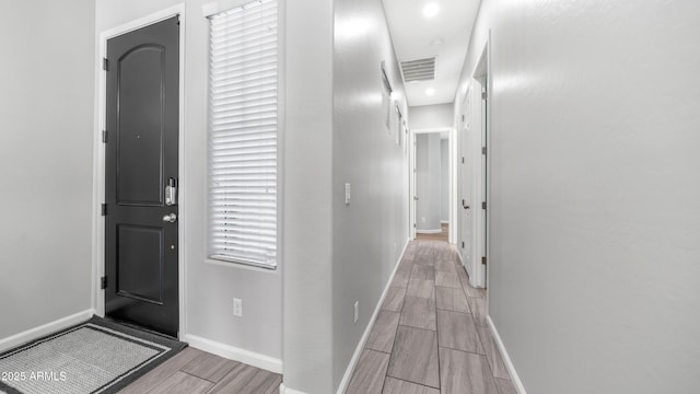corridor featuring wood tiled floor, visible vents, and baseboards