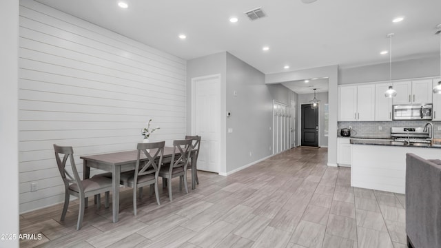 kitchen featuring recessed lighting, decorative backsplash, stainless steel microwave, white cabinetry, and visible vents