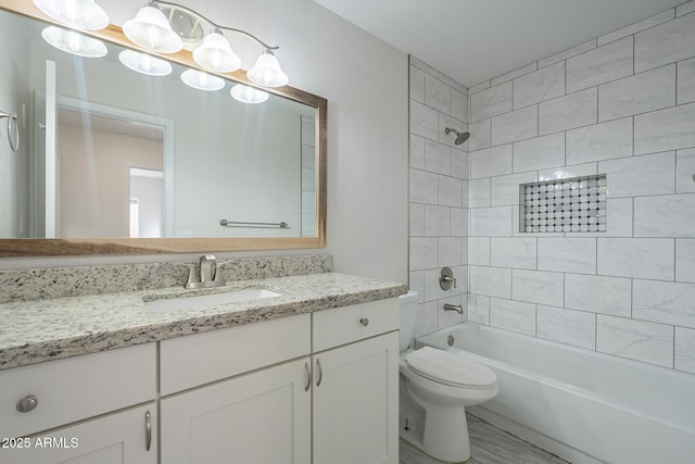 full bathroom featuring tiled shower / bath combo, vanity, and toilet