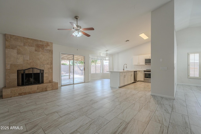 unfurnished living room featuring vaulted ceiling, ceiling fan, a fireplace, and sink