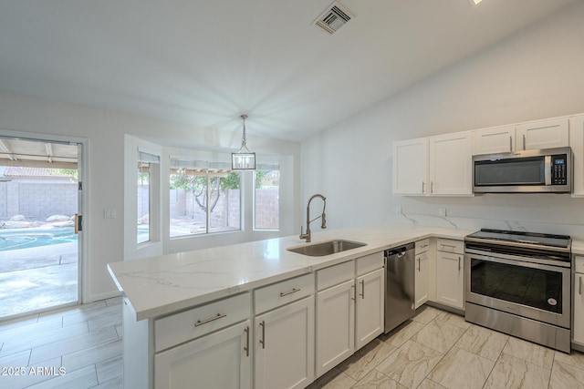 kitchen with sink, appliances with stainless steel finishes, white cabinetry, decorative light fixtures, and kitchen peninsula