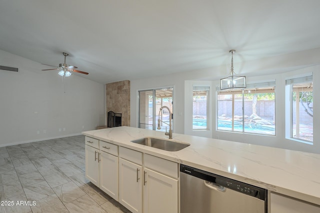 kitchen featuring sink, dishwasher, plenty of natural light, light stone countertops, and white cabinets