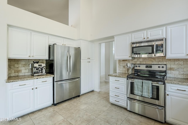 16254 N 48th Way, Scottsdale, AZ 85254 - kitchen featuring appliances with stainless steel finishes, decorative backsplash, light tile patterned floors, white cabinets, and a high ceiling