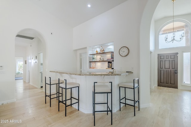 16254 N 48th Way, Scottsdale, AZ 85254 - kitchen featuring a high ceiling, a chandelier, arched walkways, light stone countertops, and a kitchen breakfast bar