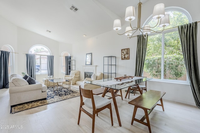 16254 N 48th Way, Scottsdale, AZ 85254 - dining space featuring light wood finished floors, a glass covered fireplace, lofted ceiling, and a chandelier