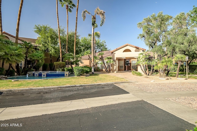view of front of property with stucco siding, a front yard, and a tile roof