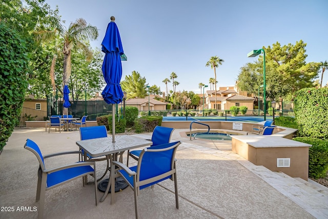 view of patio featuring fence, a community hot tub, and outdoor dining space