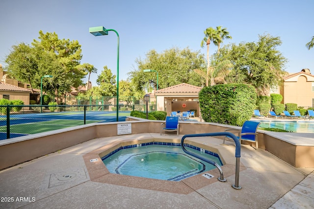 view of swimming pool featuring fence, a tennis court, and a community hot tub