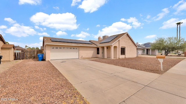 ranch-style home with a garage, stucco siding, concrete driveway, and roof mounted solar panels