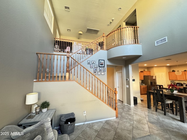 stairway with a towering ceiling and tile patterned floors