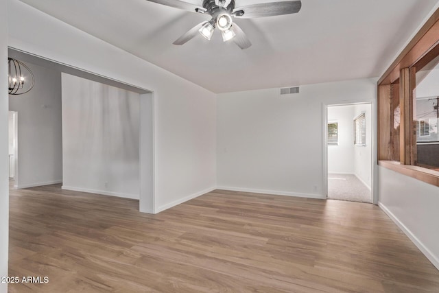 unfurnished room with hardwood / wood-style floors and ceiling fan with notable chandelier