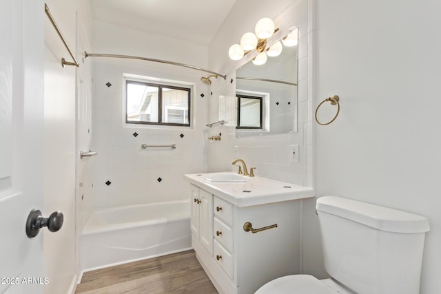 full bathroom with tiled shower / bath, wood-type flooring, decorative backsplash, vanity, and toilet