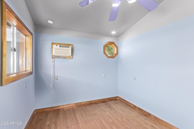 empty room featuring ceiling fan, a wall unit AC, and light wood-type flooring