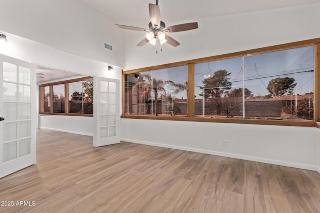 empty room with ceiling fan, light wood-type flooring, and french doors