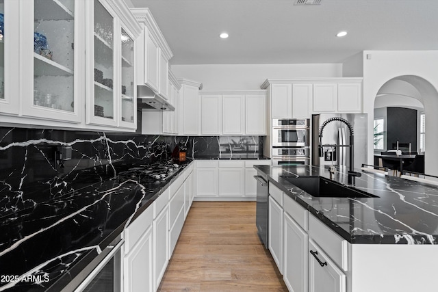 2722 W Hiddenview Dr, Phoenix, AZ 85045 - kitchen with a sink, a kitchen island with sink, arched walkways, under cabinet range hood, and appliances with stainless steel finishes