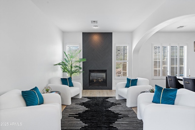 2722 W Hiddenview Dr, Phoenix, AZ 85045 - living area featuring arched walkways, wood finished floors, a fireplace, and healthy amount of natural light