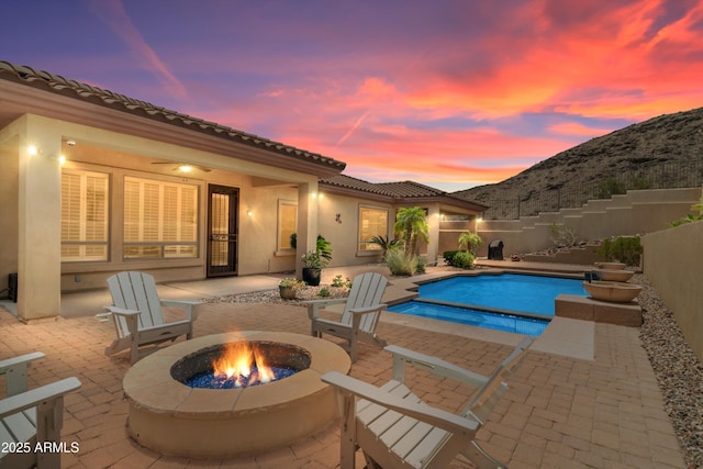 2722 W Hiddenview Dr, Phoenix, AZ 85045 - pool at dusk featuring an outdoor fire pit, a patio area, a mountain view, a fenced backyard, and a pool with connected hot tub