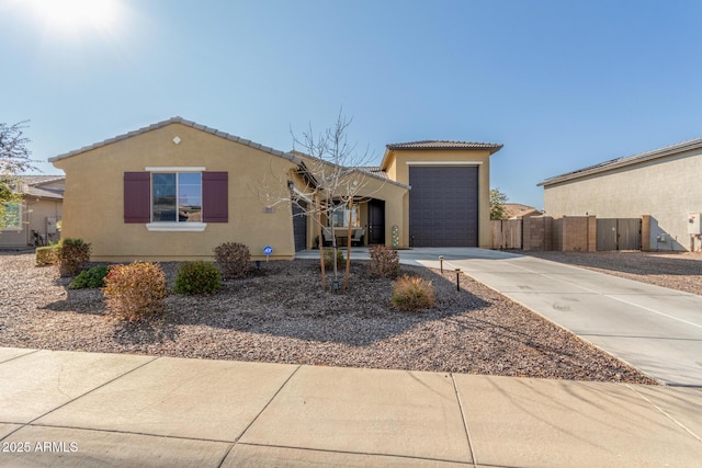 view of front of house featuring fence, an attached garage, stucco siding, concrete driveway, and a tile roof