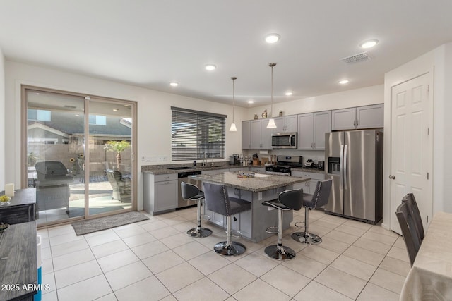 kitchen featuring visible vents, a breakfast bar, gray cabinets, appliances with stainless steel finishes, and light tile patterned flooring