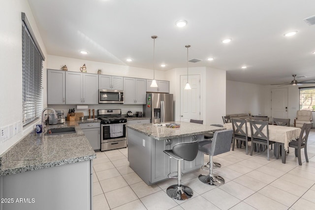 kitchen featuring a sink, a kitchen island, gray cabinets, and stainless steel appliances