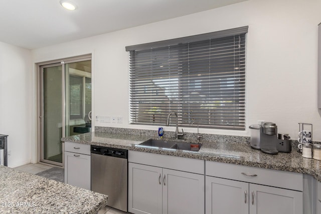 kitchen with light tile patterned floors, dishwasher, light stone countertops, and a sink